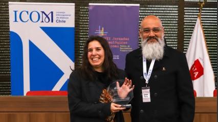 Figura femenina recibe un reconocimiento por parte de una figura masculina